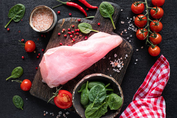 Raw turkey fillet ready for grilling. Chicken fillet on a wooden cutting board with cherry...