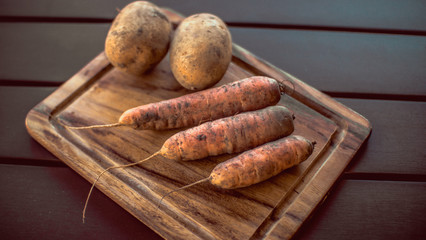 Potatoes and carrots crop on a wooden garden table background