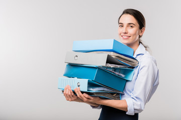 Young elegant female accountant with stack of folders with financial documents
