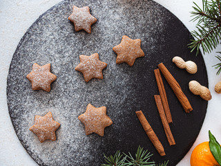 Homemade Christmas shortbread star shape sugar cookies with sugar powder, cinnamon, nuts, and cookie. Christmas baking. Overhead view. New year treat for Santa Claus cooking on a black board Homemade