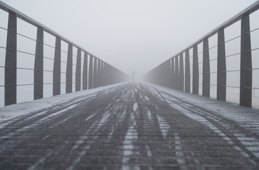 Slippery bicycle bridge during a foggy, winter morning.