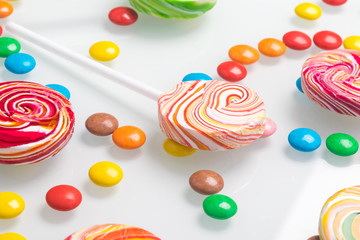 concept of caramel colored lollipops and chocolate dragees on a light background