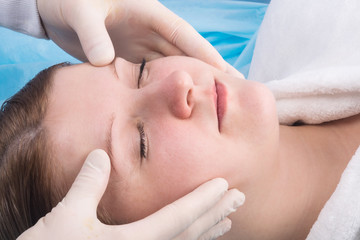 young woman gets facial massage in spa salon, close-up
