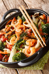 seafood stir-fried with fresh vegetables close-up in a pan. vertical