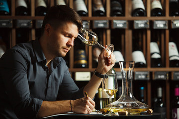Sommelier degustating white wine poured in glass