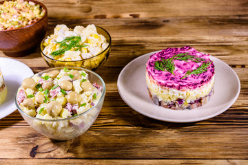 Set of festive mayonnaise salads on wooden table