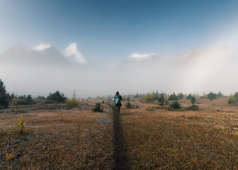 Man backpacker trekking on field with rocky mountains in foggy at provincial park