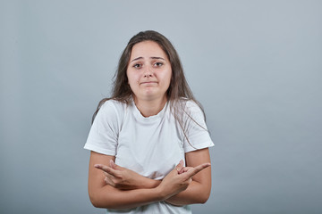 Girl in white t-shirt ahead isolated gray background undecided pointing fingers in different directions with doubts