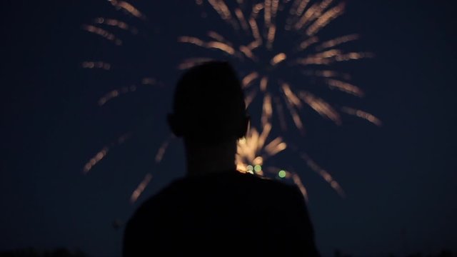 Blurred closeup silhouette of a man enjoying fireworks at night