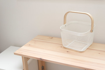 Fototapeta na wymiar シンプルな白いかご　１　カゴ　収納　洗濯　キッチン　白　空っぽの　白背景　テーブル　木　部屋　コピースペース　文字スペース