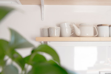 Fototapeta na wymiar キッチン棚とマグカップとティーポット　料理　コーヒー　茶　棚　背景　白背景　余白　白壁　ホワイトスペース　コピースペース　文字スペース　空間　部屋　木　デザイン　