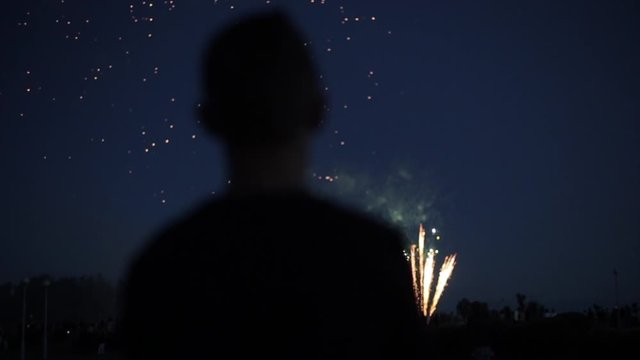 Blurred closeup silhouette of a man enjoying fireworks at night