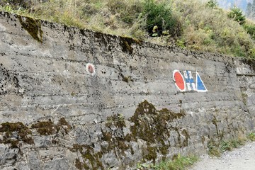 trail signs painted on a wall in the begin of a route in the mountains.