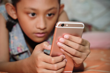 Southeast Asian Teenage Girl Enjoy Playing Her Smartphone While Resting on Bed
