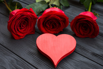 Red heart and red roses on dark wooden background