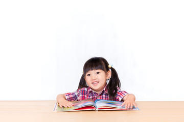 白背景の前で本を読む幼い女の子。幼児、教育、読書、学習、成長、育児イメージ