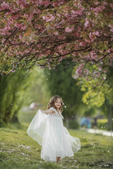 Obraz na płótnie Canvas A girl with long white hair in a white dress like a bride walks in the Park alone.