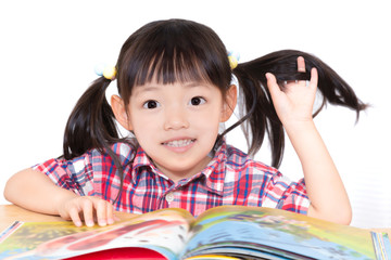 白背景の前で本を読む幼い女の子。幼児、教育、読書、学習、成長、育児イメージ