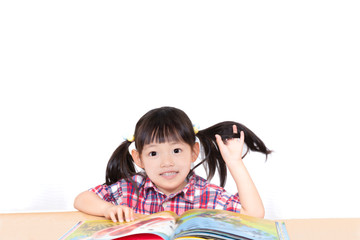 白背景の前で本を読む幼い女の子。幼児、教育、読書、学習、成長、育児イメージ