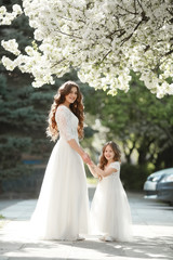 Mother dressed in a white dress as a bride walks in the Park with her daughter.