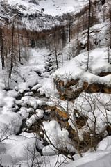 Fototapeta premium Alpine mountain river in winter on a cloudy day