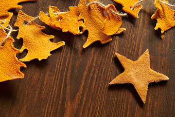 Obraz premium Christmas and new year holiday concept with copy space - handmade decoration from dried peel of oranges in a fir tree shape on a dark wood background