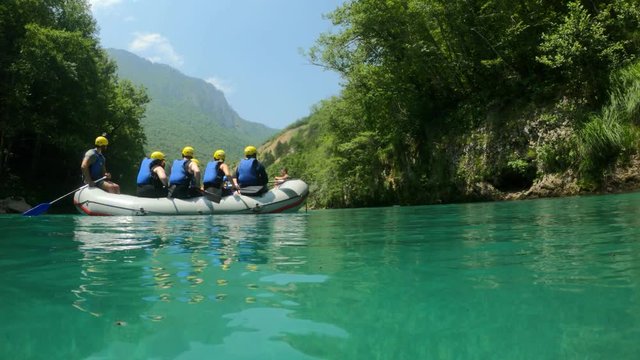 Group of Tourists on a boat sailing along a mountain river Tara during rafting before extreme rapids. Entertainment program Montenegro. Crystal clear water, beautiful nature landscape with mountains
