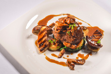 Italian food - Pan Fried beef tenderloin, Duck foie gras, potato anna, black truffel and Barollo wine sauce on White Plate.
