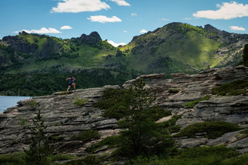 A man running on the rocks in the midst of a magnificent mountain landscape.  Bayanaul National Park
