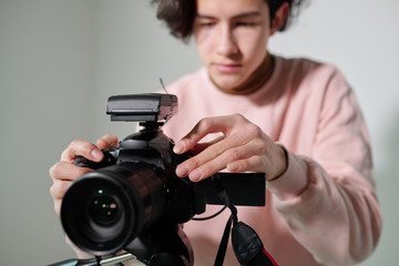 Hands of young cameraman in powdery pink sweatshirt regulating video equipment