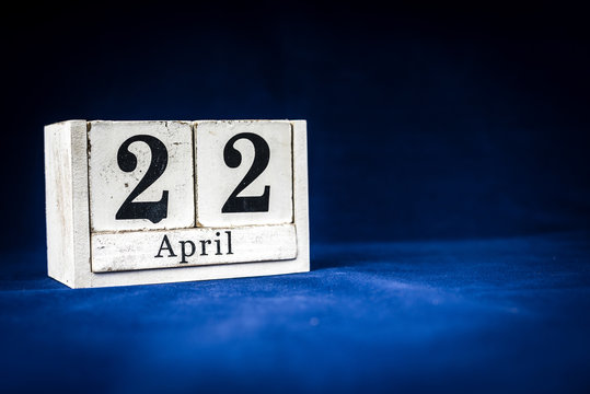 April 22nd, Twenty-second of April, Day 22 of month April - rustic wooden white calendar blocks on dark blue background with empty space for text.