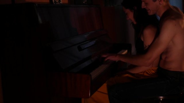 The half-hearted boyfriend and girlfriend hug. A man hugs a girl and plays the piano in a dark room. Romantic atmosphere.