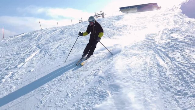 Young adult recreational skier enjoys idyllic perfect weather in cold winter. Skiing alone on perfectly groomed ski piste at ski resort