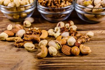 Various nuts (almond, cashew, hazelnut, pistachio, walnut) in glass bowls on a wooden table. Vegetarian meal. Healthy eating concept