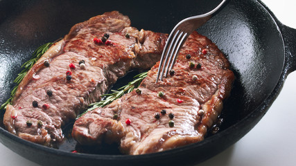 Raw fresh meat Steak Striploin for two on frying pan Striploin beef steak cooked in iron skillet closeup view. Delicious juicy meat and fork preparing on iron pan Concept for a tasty and healthy meal.