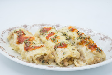 Canelones (cannelloni) with meat filled pasta and cheese and tomato on a plate
