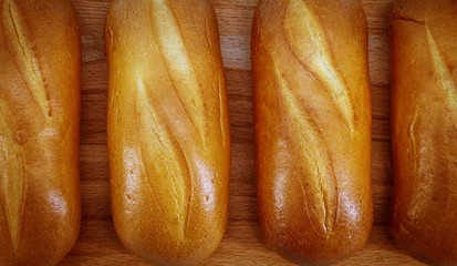 Fresh baked white bread with a Golden crust lies on a wooden Board for slicing. Close up