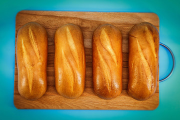 On a blue background on a wooden Board lies fresh white bread