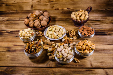 Various nuts (almond, cashew, hazelnut, pistachio, walnut) in bowls on a wooden table. Vegetarian meal. Healthy eating concept