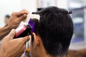 The barber is cutting the hair for customers in the barber shop.