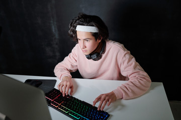 Serious teenager with headphones around neck pressing keys of keypad