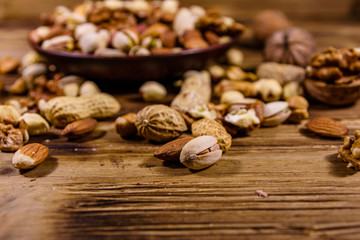 Various nuts (almond, cashew, hazelnut, pistachio, walnut) in ceramic plate on a wooden table. Vegetarian meal. Healthy eating concept