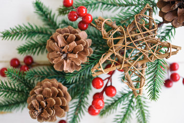 Fototapeta na wymiar White wood texture with pine leaf, pine cones or conifer cone, red holly balls and wooden star in Christmas concept. Wood plank background in top view flat lay with copy space for Christmas wallpaper.