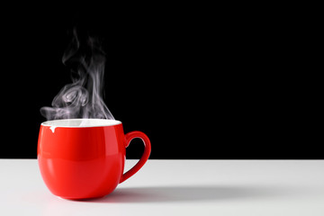 Steaming coffee cup on black background. Red сoffee cup with steam. Smoke from hot coffee. Front...