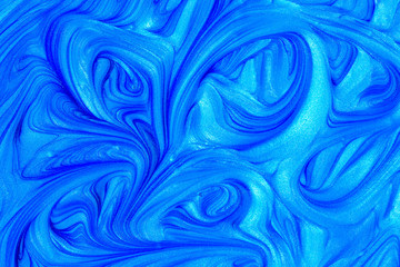 Close up liquid luxury blue metallic glitter paint swirls to make an abstract textured background