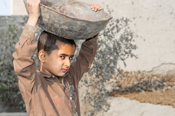 a very young orphan child is forced into child labor and working at a construction site and his...