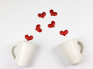 Flat layout of red glitter hearts spread out from two white cup of coffee.Valentine's day concept.