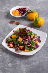 Mixed salad with swiss chard leaves, tangerines, pomegranate, pecan and toast star on top. Holiday salad looks like Christmas tree.