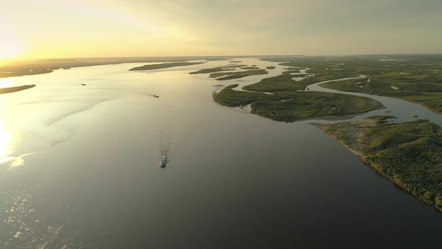 Helicopter picturesque widest river Lena Russia Siberia beautiful natural landscape orange sunset over rugged delta channel island. Barge ships are sailing. Best unique places Yakutia permafrost taiga