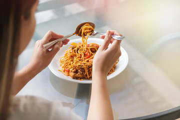 close up of woman eating spaghetti with fork and tablespoon